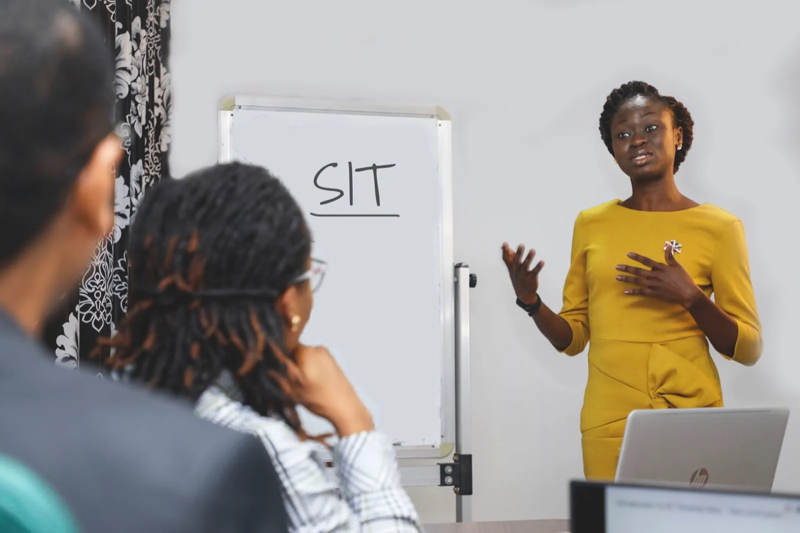 A facilitator leading a session with the letters SIT written on a flip chart while participants look on